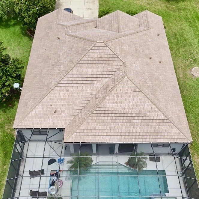 Aerial view of a house with a beige roof and screened patio overlooking a swimming pool.