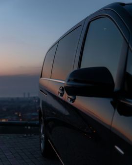 Black SUV parked at sunset, with city skyline blurred in the background.