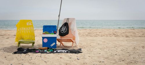 Beach chairs and coolers on a sandy shore beside the ocean