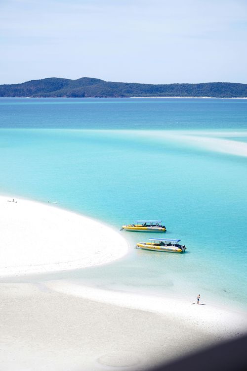 Turquoise tropical bay with white sand and two small boats near the shore