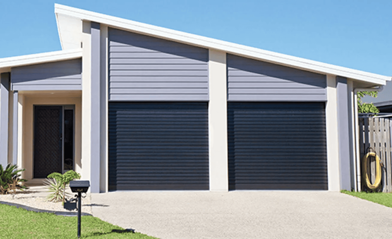 A modern house with two garage doors and a mailbox in front of it.