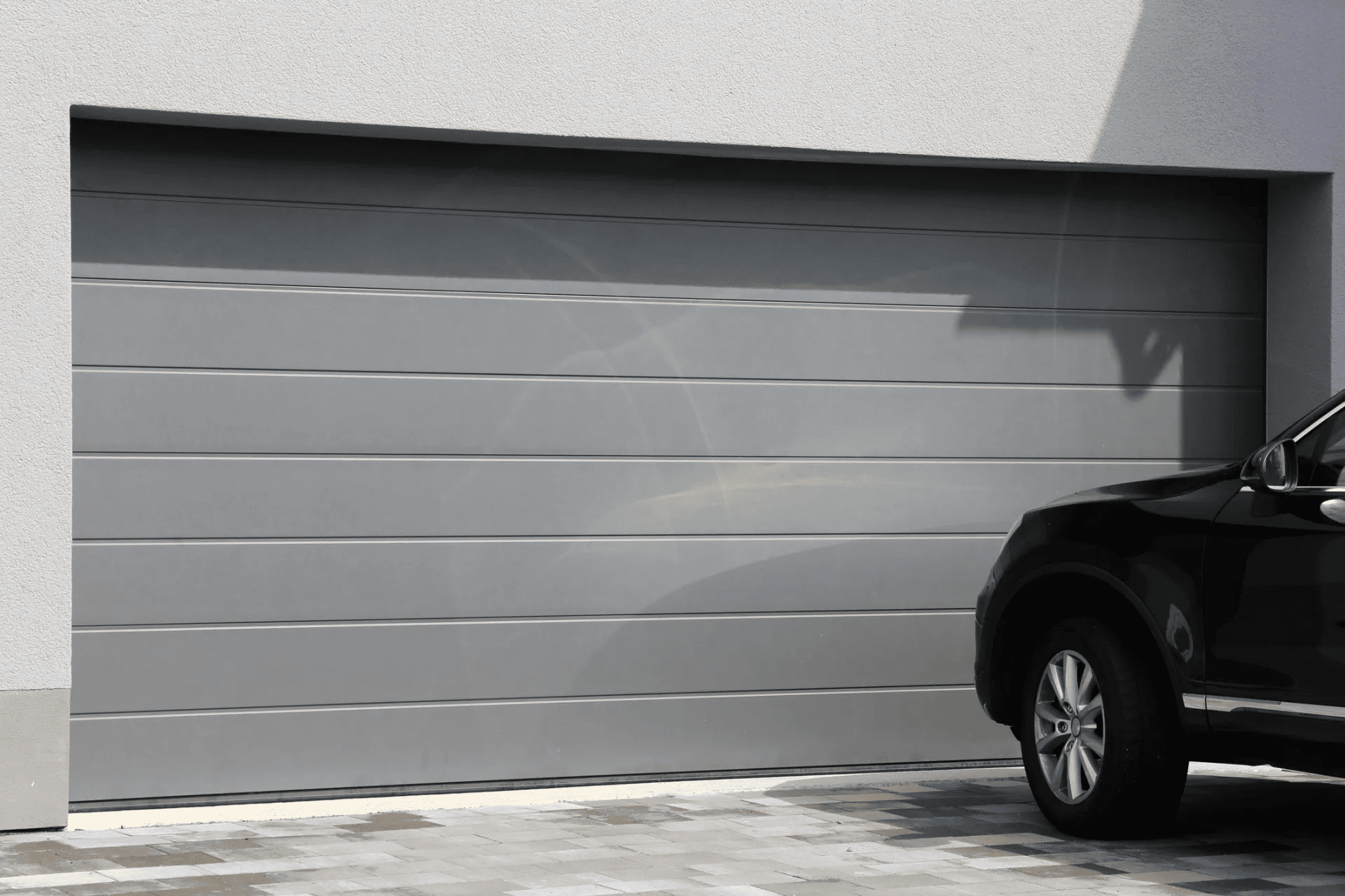 A car is parked in front of a garage door.