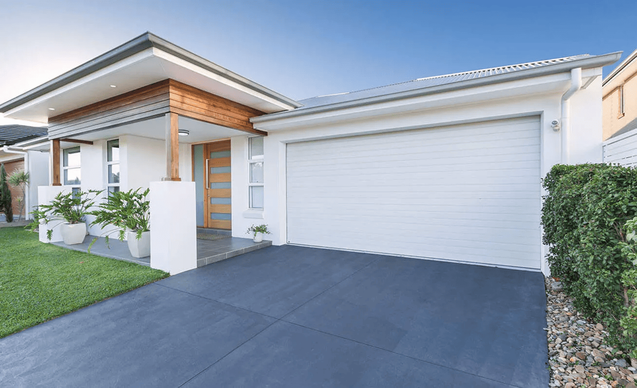 A white house with a white garage door and a black driveway.