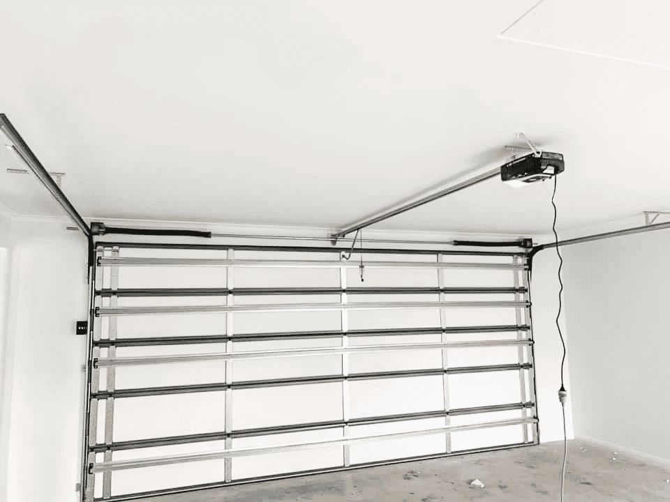 A black and white photo of an empty garage with a garage door open.