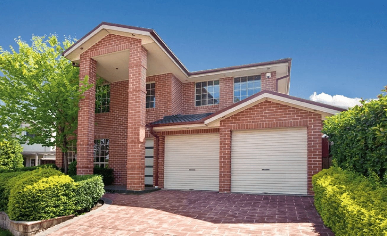A large red brick house with two white garage doors