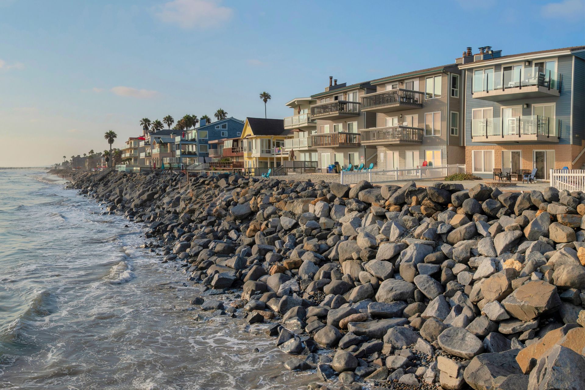 Coastal buildings line a rocky shore, with the ocean visible.