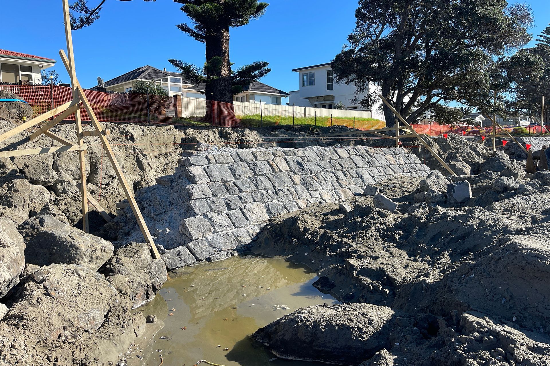 A seawall being constructed at a beach, with mud and construction materials.