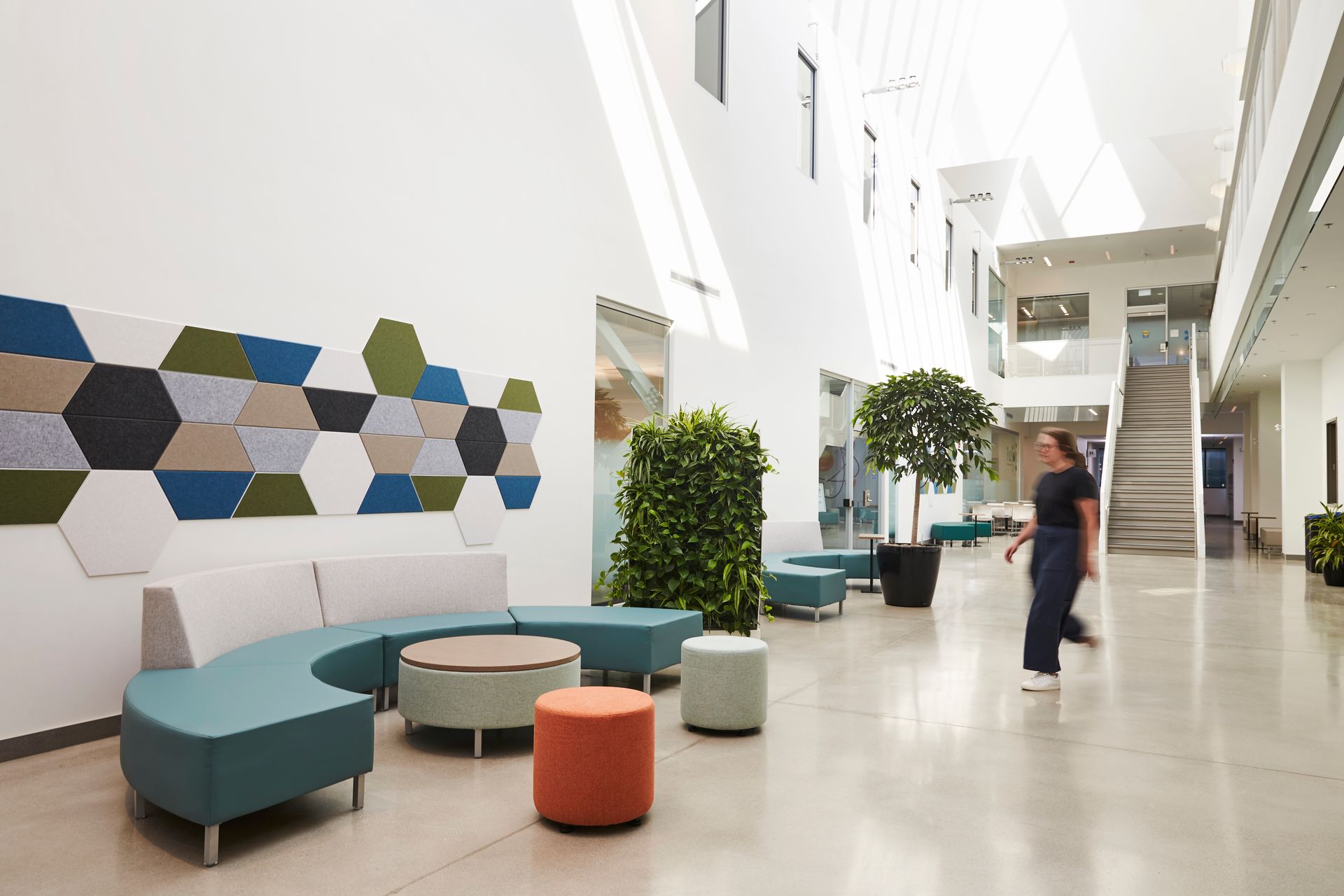 A thoughtfully designed commercial common lobby area with colourful welcoming seating, acoustic wall decor and plants