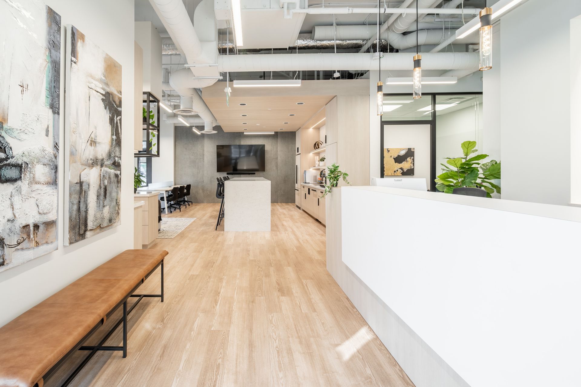 A thoughtfully designed commercial office space with a reception desk, bench, art and looking into a shared staff kitchen and lounge coworking space