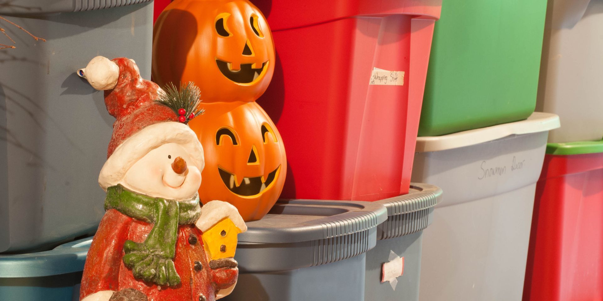A snowman figure with jack-o-lanterns and storage bins stacked together.