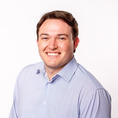 Smiling man in a light blue striped shirt against a white background