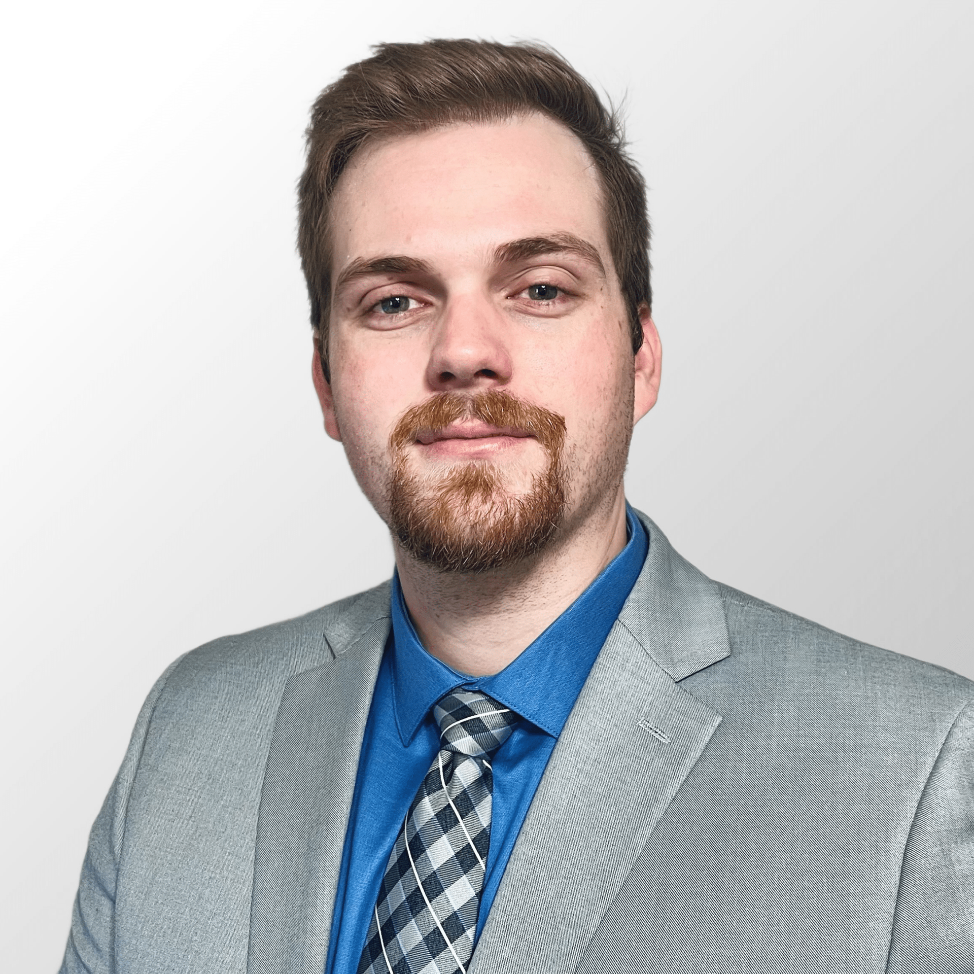 Portrait of a man in a light gray suit and blue shirt against a white background