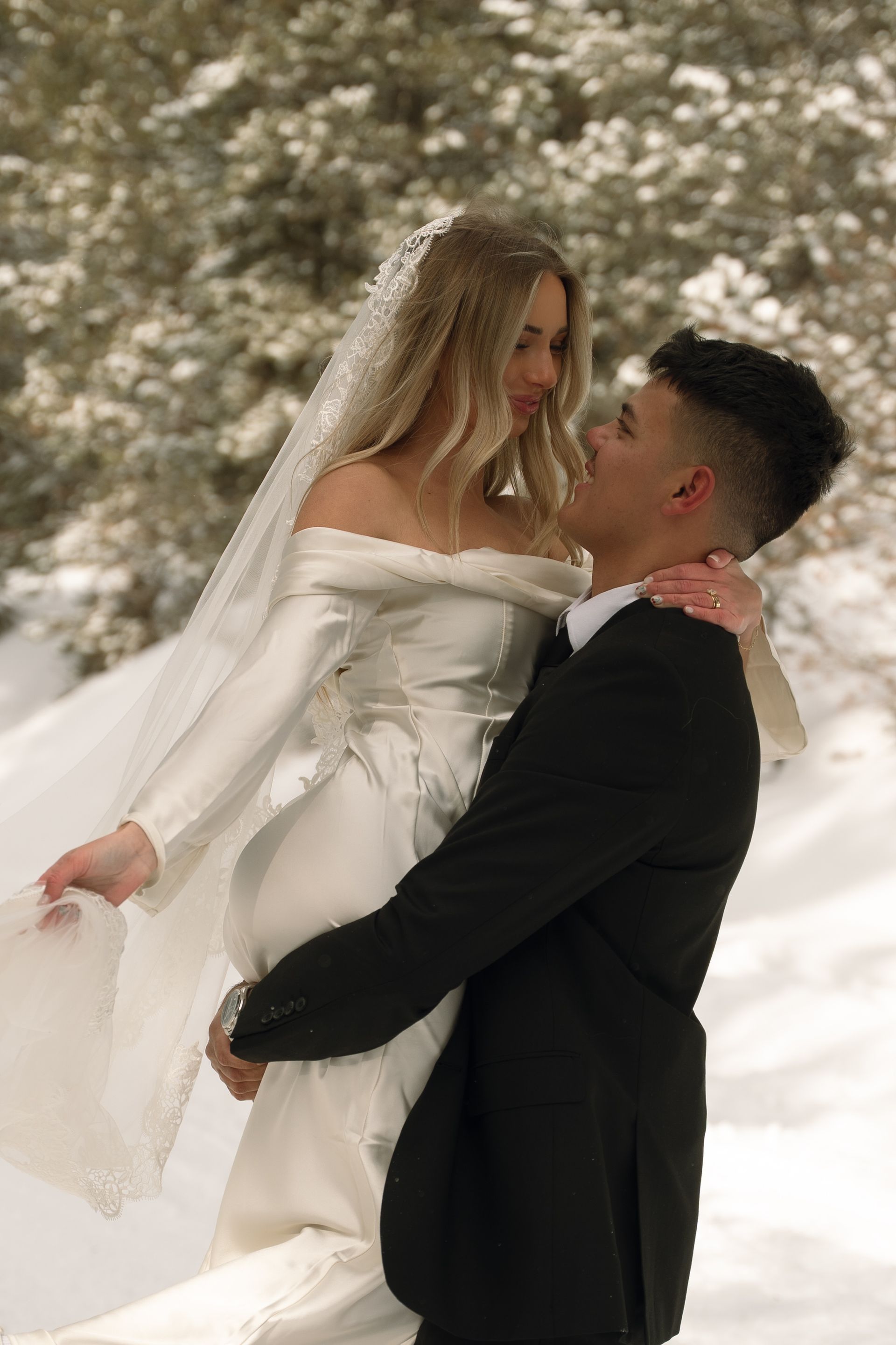 A bride and groom are posing for a picture in the snow.