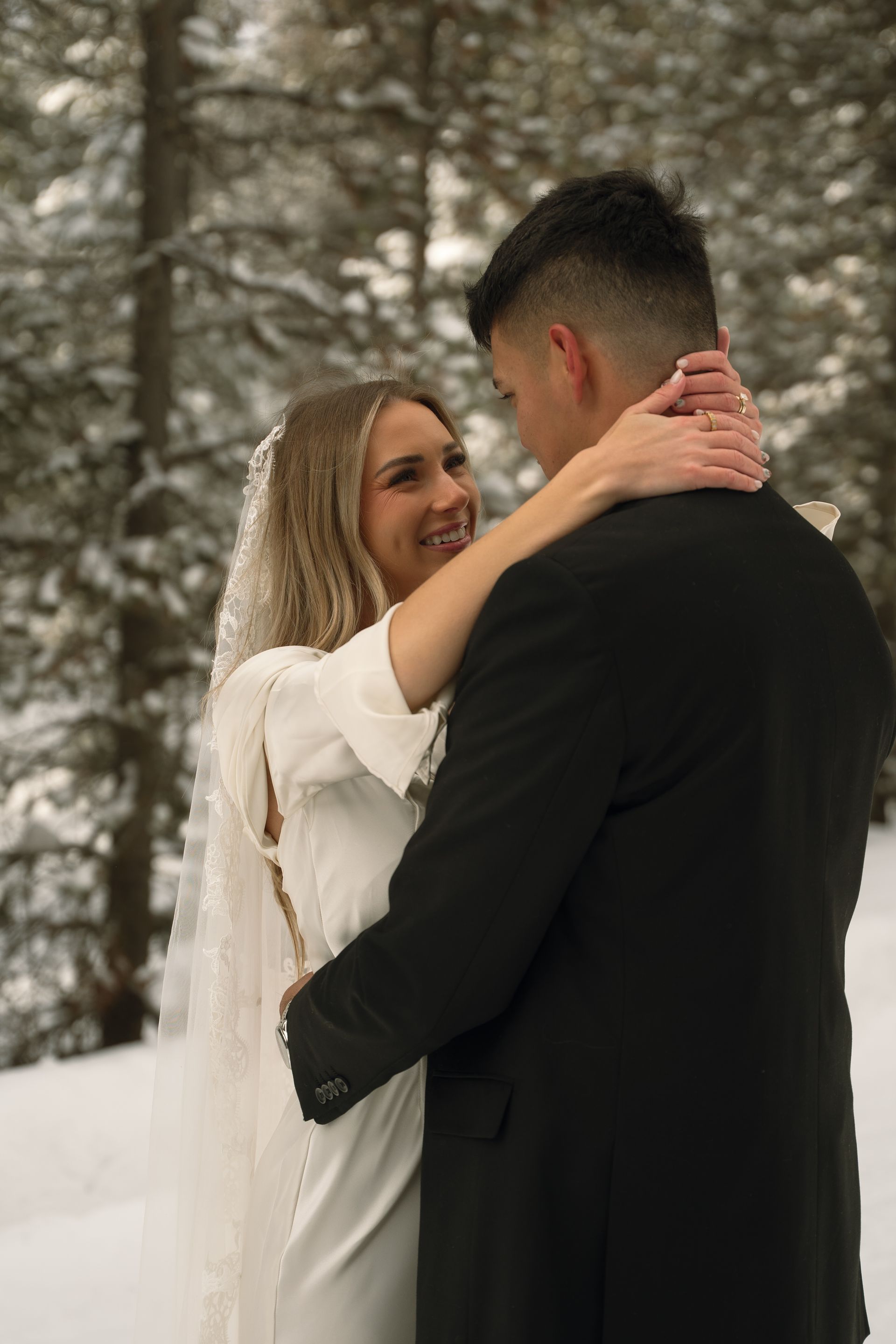 A bride and groom are posing for a picture in the snow.