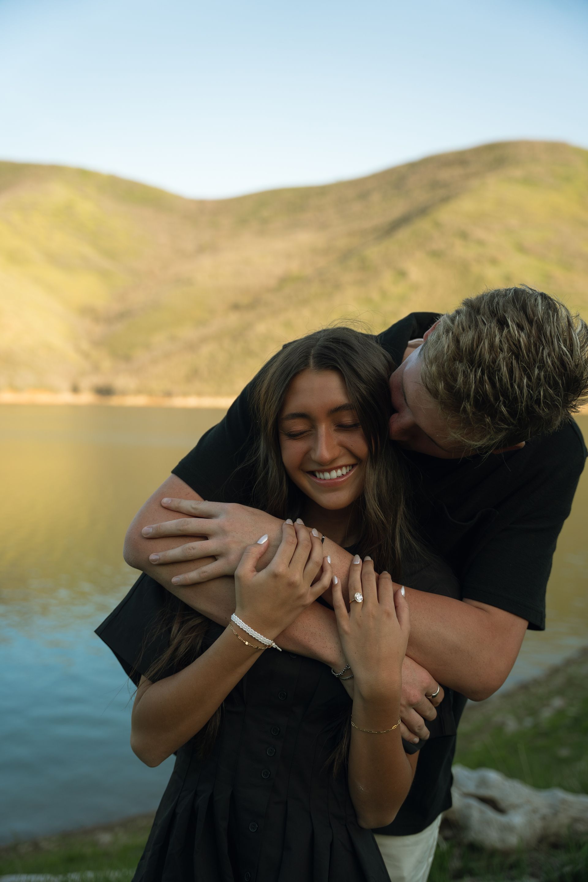 A man is hugging a woman in front of a lake.