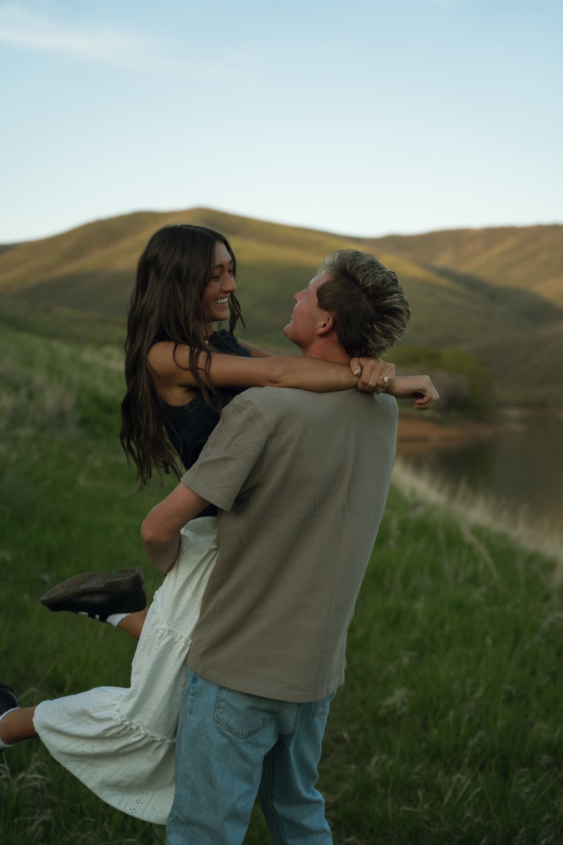 A man is holding a woman in his arms in a field.