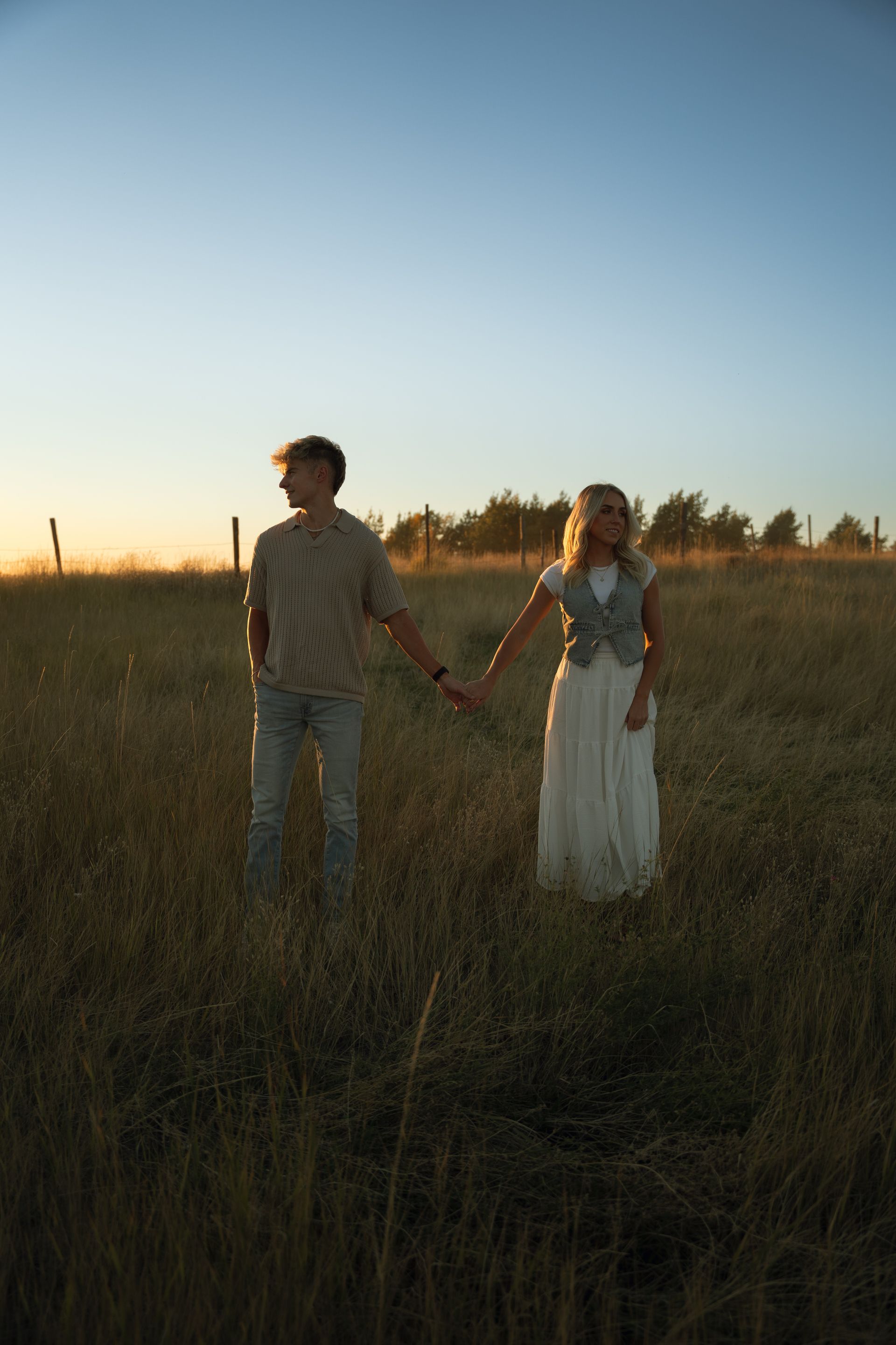 A man and a woman are holding hands in a field.