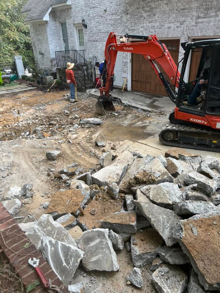 Excavator clearing rubble beside a stone building in a demolition site