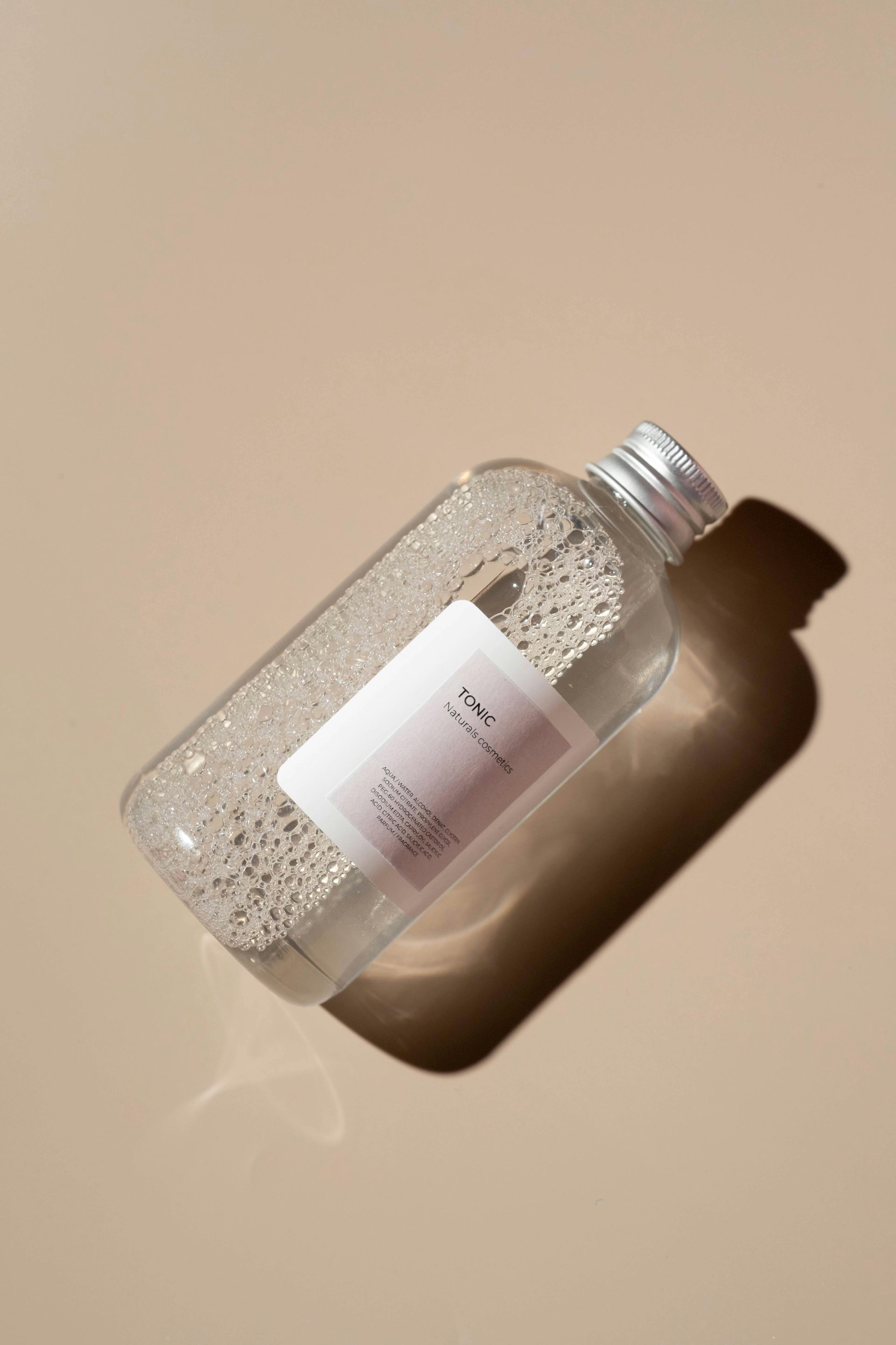 Clear bottle containing small spheres, with label, resting on tan surface.