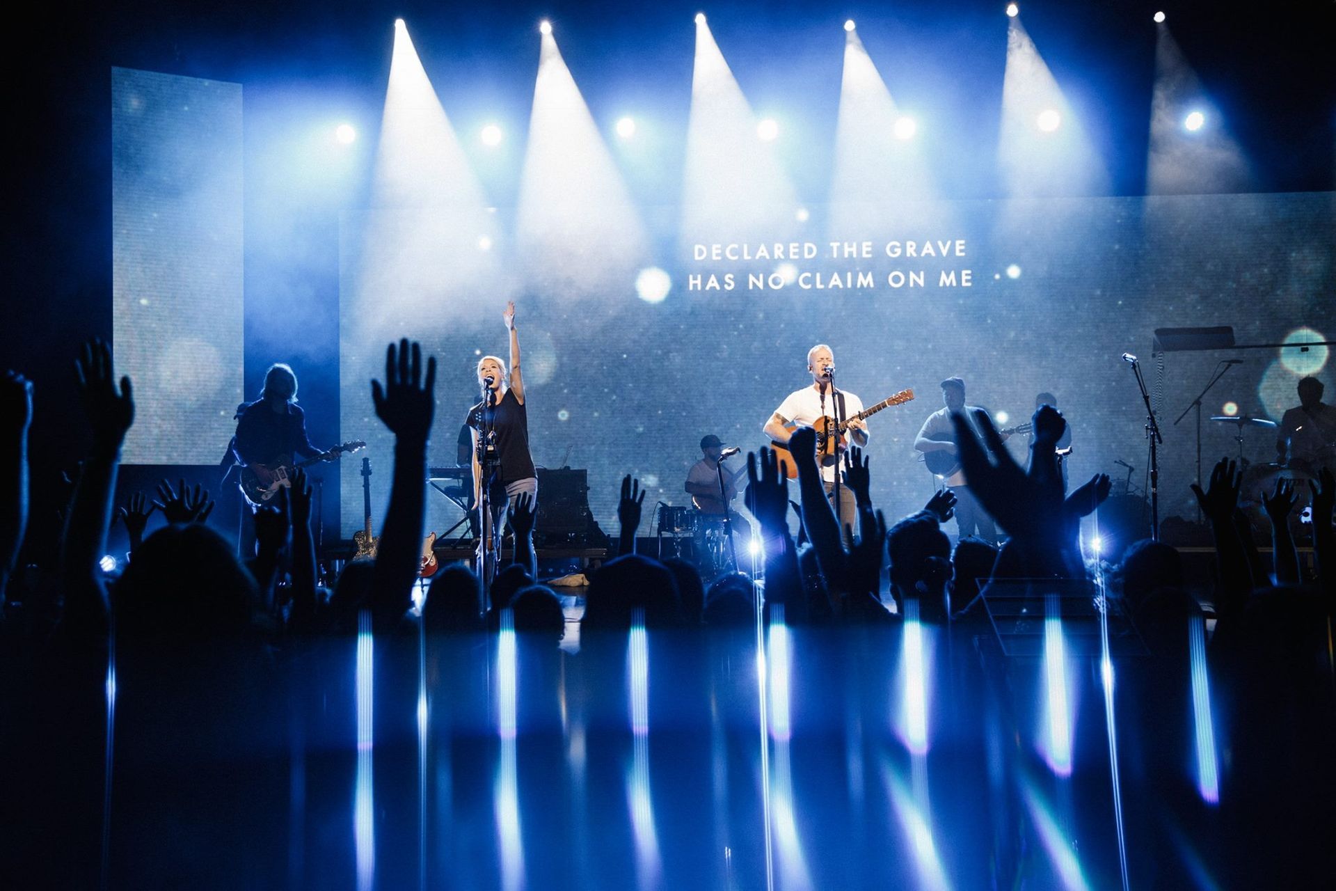 A group of people are standing on a stage with their hands in the air.