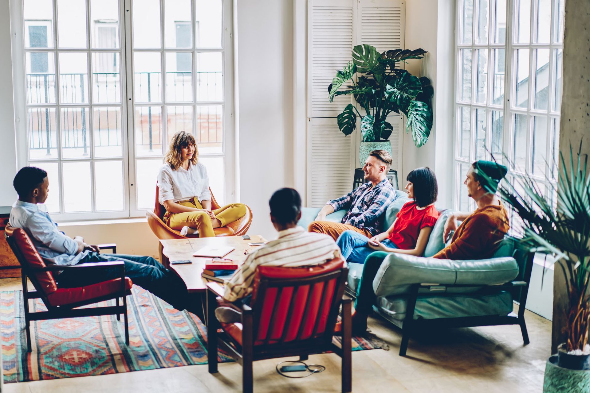 A group of people are sitting around a table in a living room.