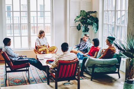 A group of people are sitting around a table in a living room.