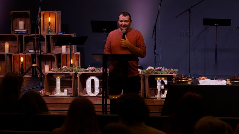 A man is standing at a podium giving a speech in front of a crowd.