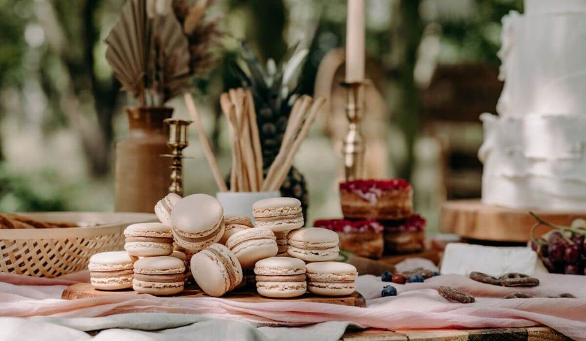 Macarons stacked on a table with other desserts, candles, and decorations in an outdoor setting.