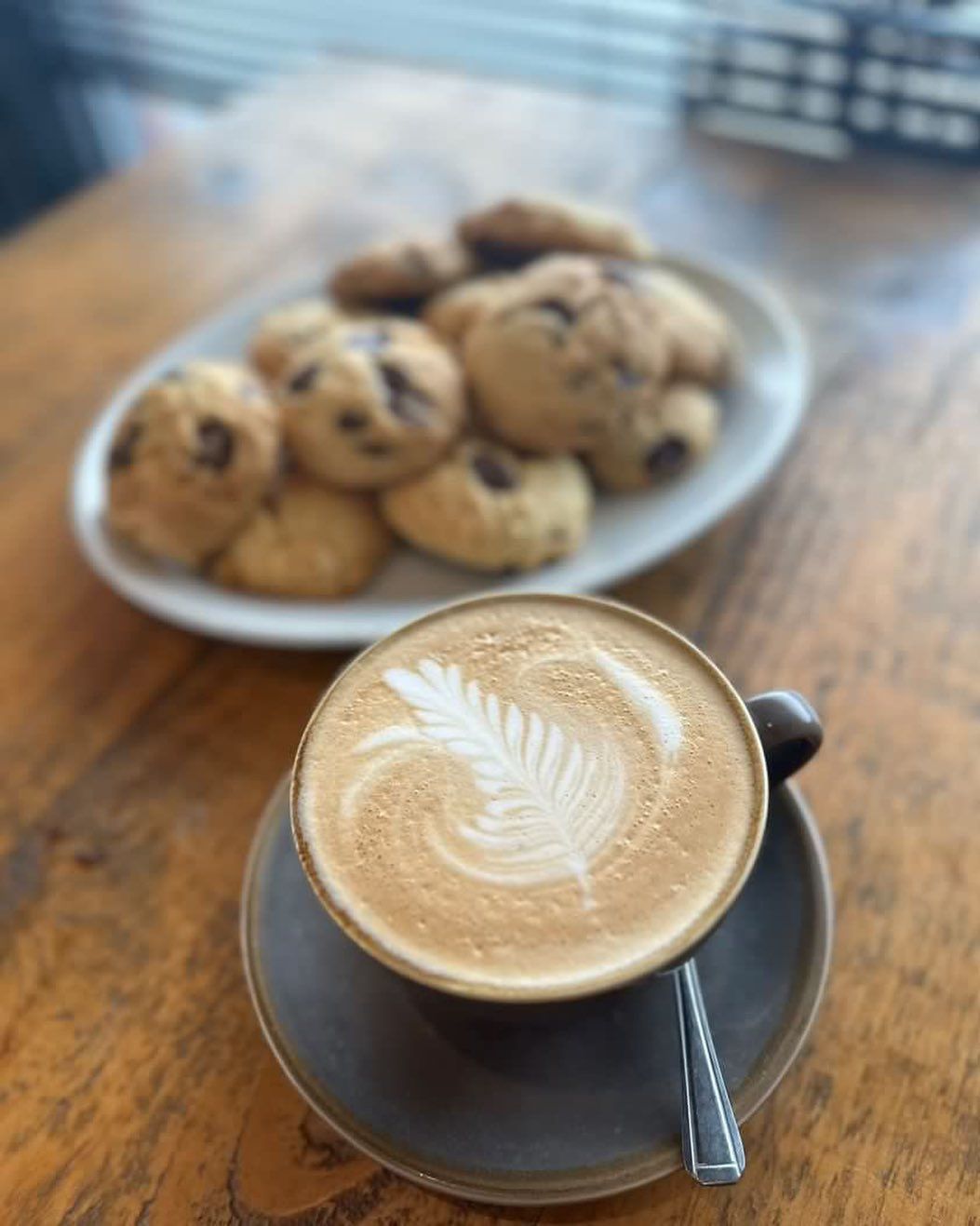 a cup of coffee on a saucer next to a plate of cookies