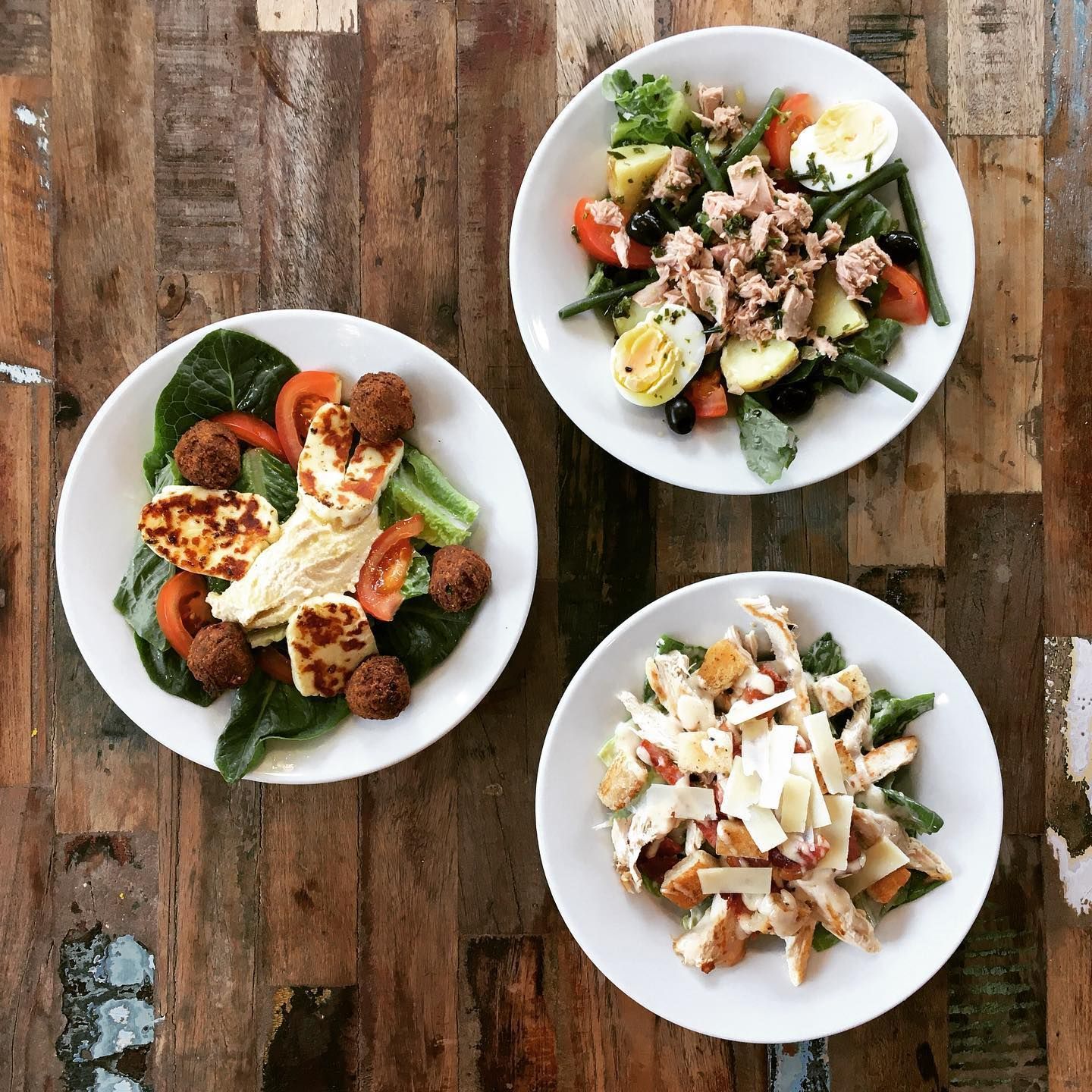three bowls of food are sitting on a wooden table