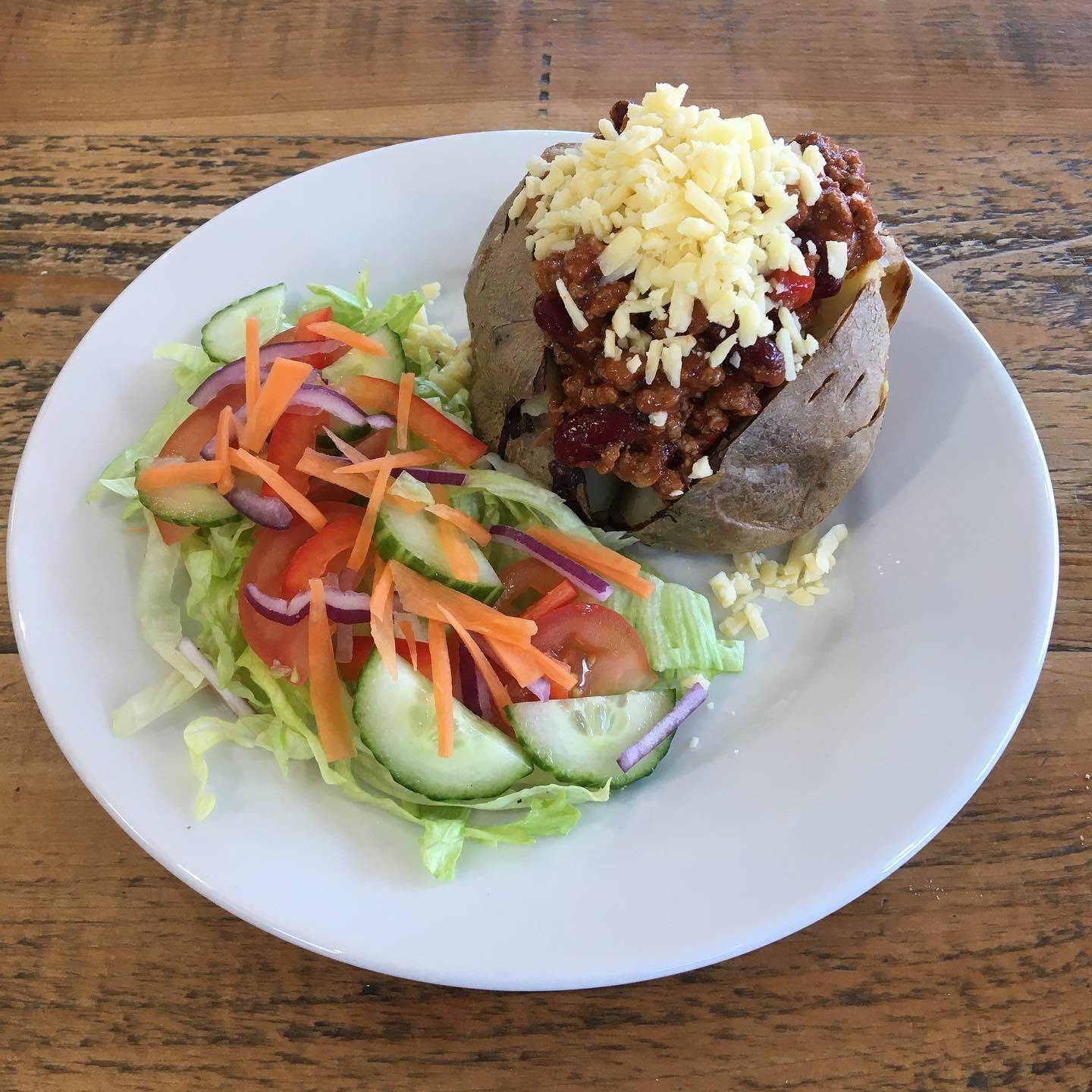 a white plate topped with a baked potato and a salad
