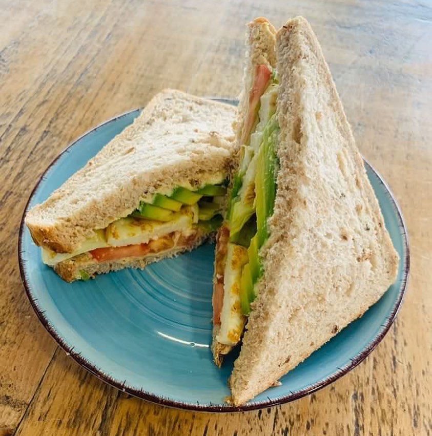 a sandwich cut in half on a blue plate on a wooden table .