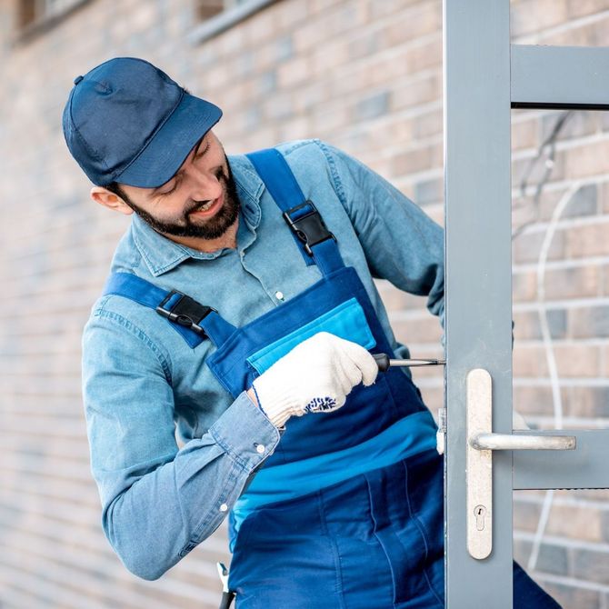 A man is working on a door with a screwdriver.