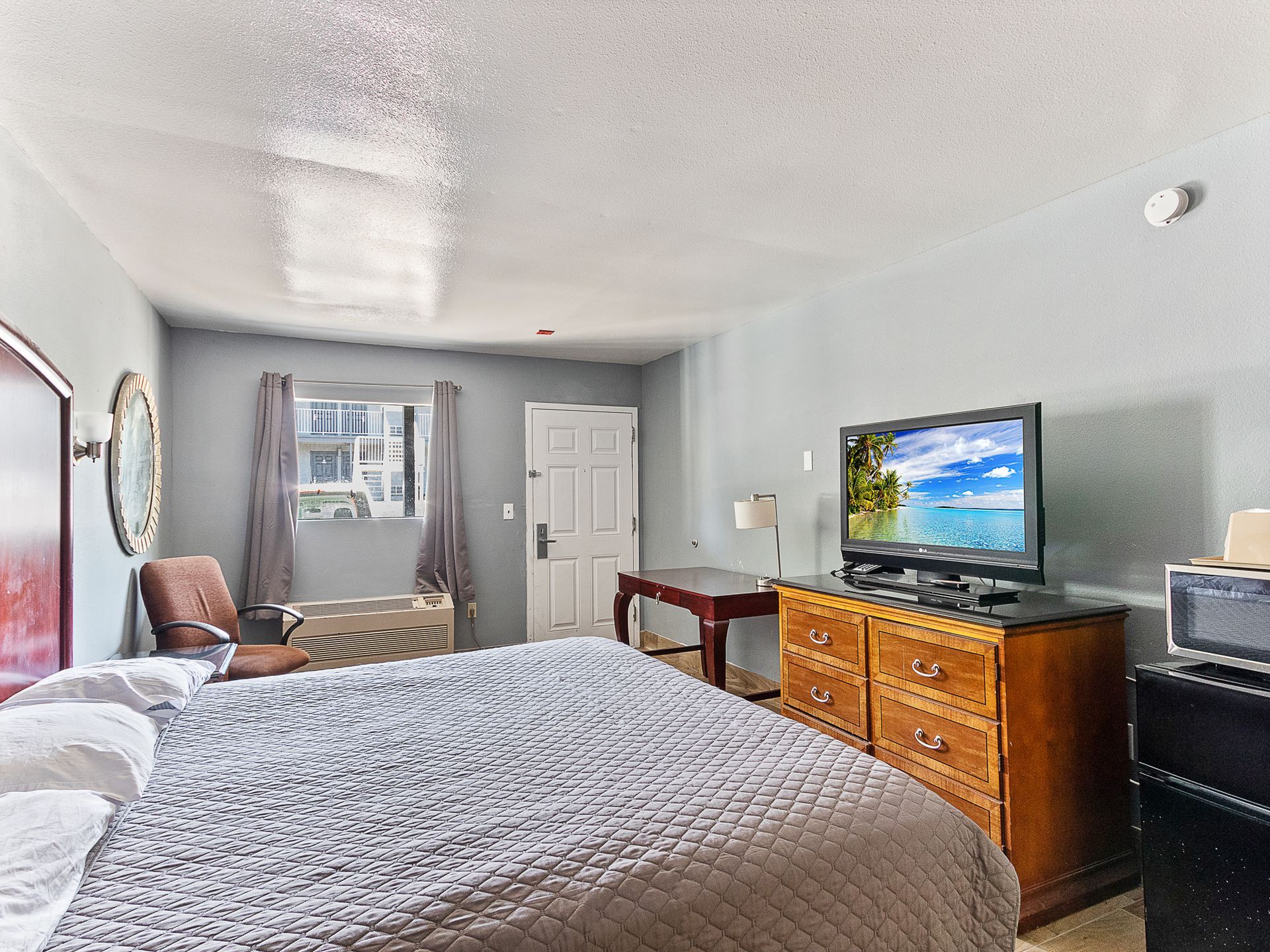 Bedroom with bed, TV, desk, and microwave.