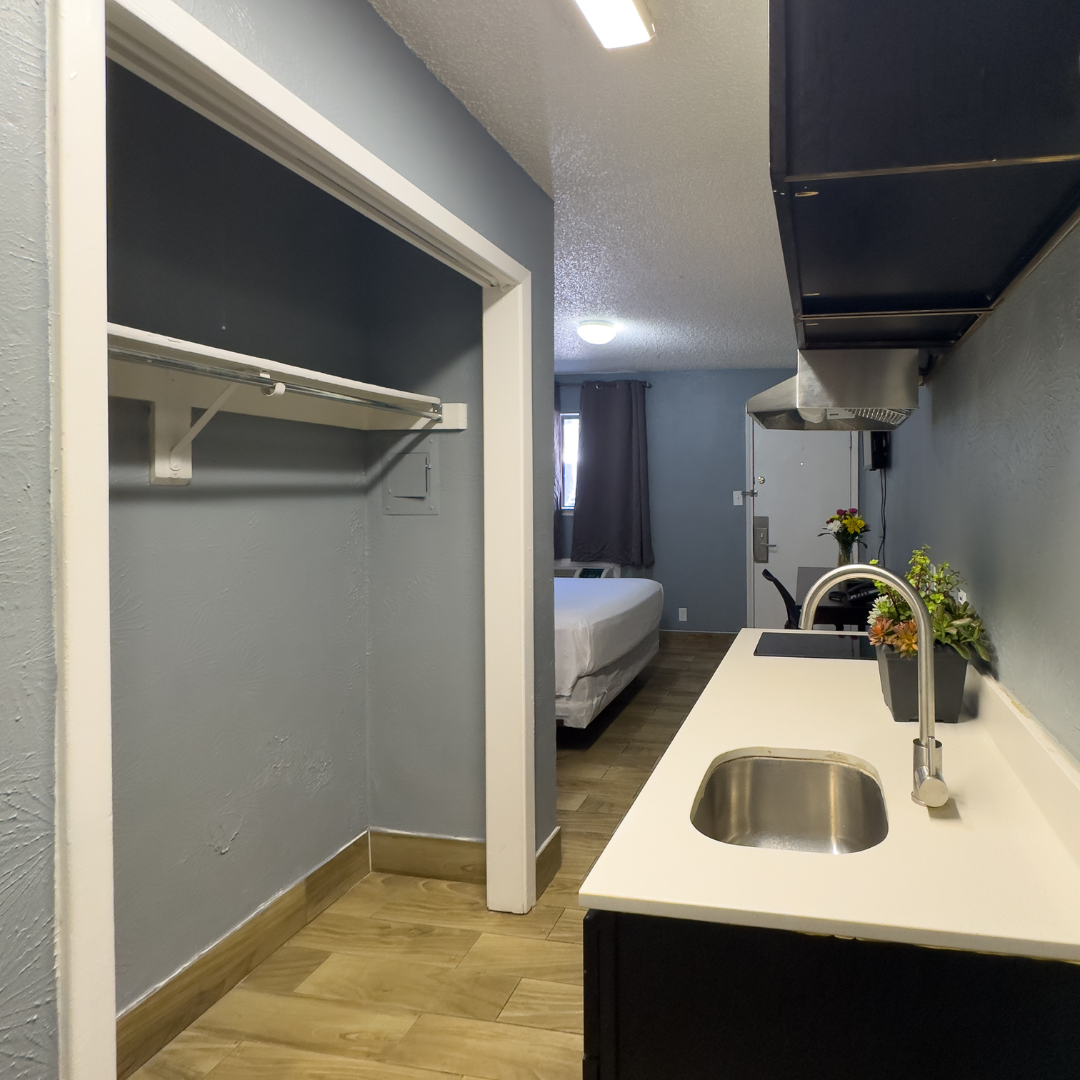 Small hotel room with a kitchenette, a closet, and a bed in the background.