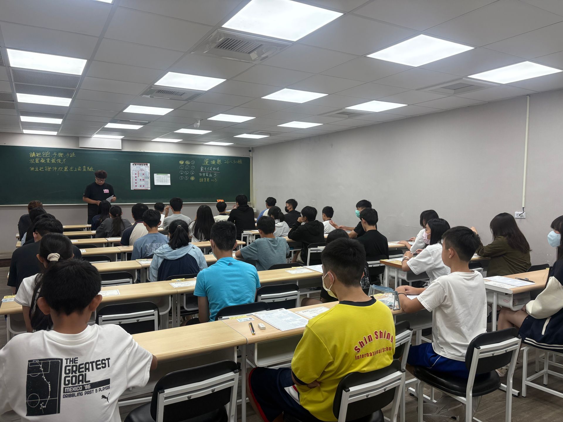 學生們坐在教室裡等待考試，老師在黑板前。