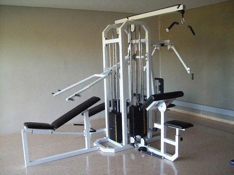 Máquina de gimnasio doméstica multiestación en una habitación beige con asientos acolchados y cables para pesas.