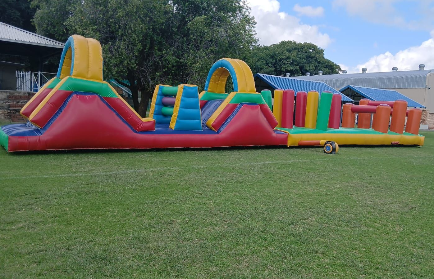 A large inflatable obstacle course is sitting on top of a lush green field.