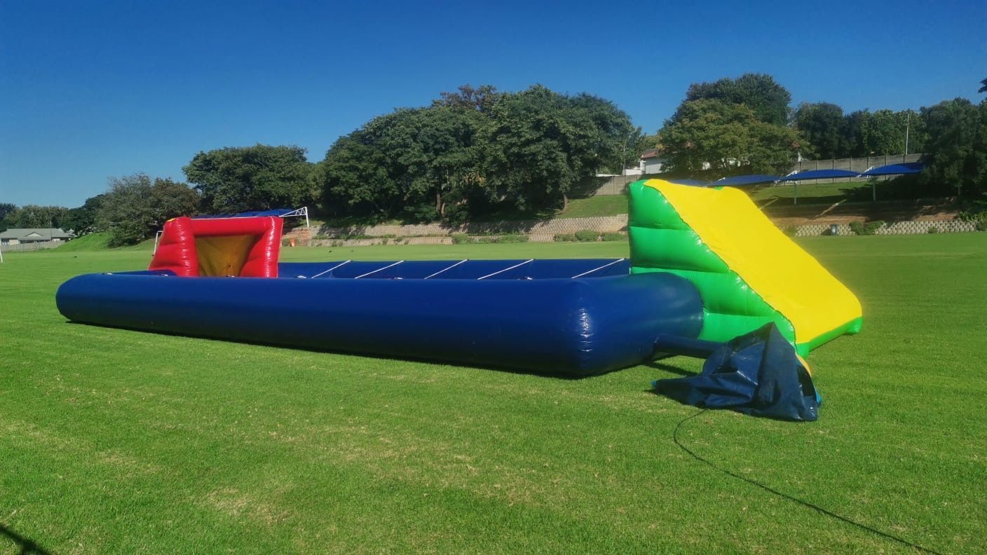A red and blue inflatable fence is sitting on top of a lush green field.