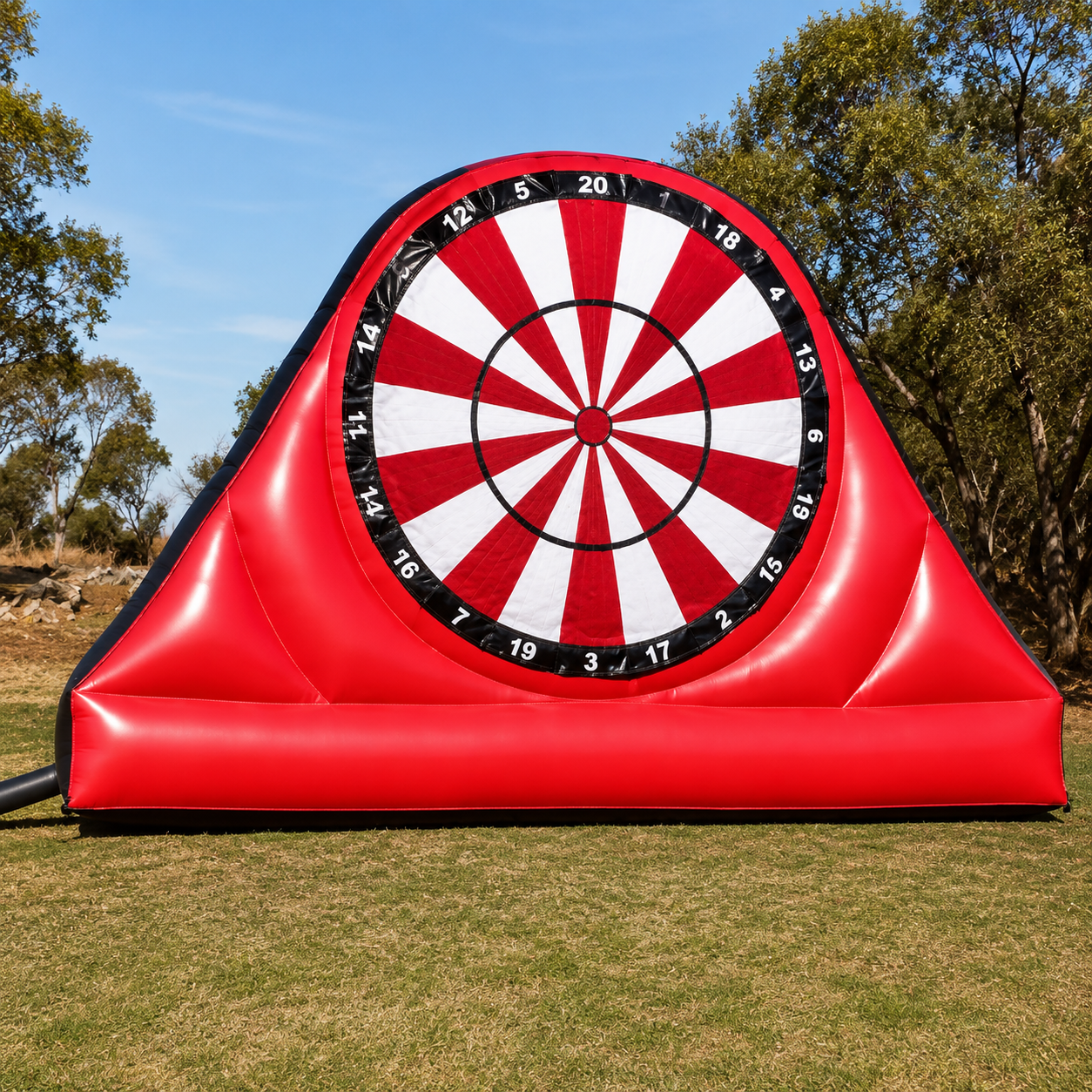 A large inflatable dart board is sitting in a grassy field.