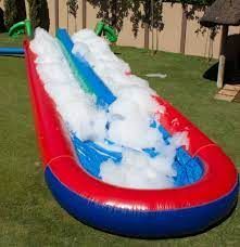An inflatable water slide filled with foam is sitting on top of a lush green field.