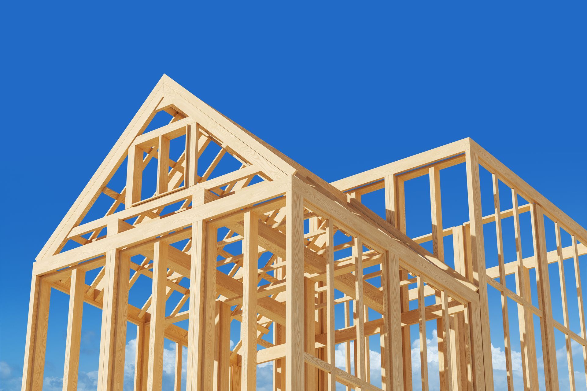 Wooden house frame under construction on a bright blue sky background, concept of home building.