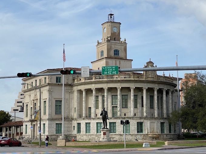 A large building with a clock tower and a statue in front of it.