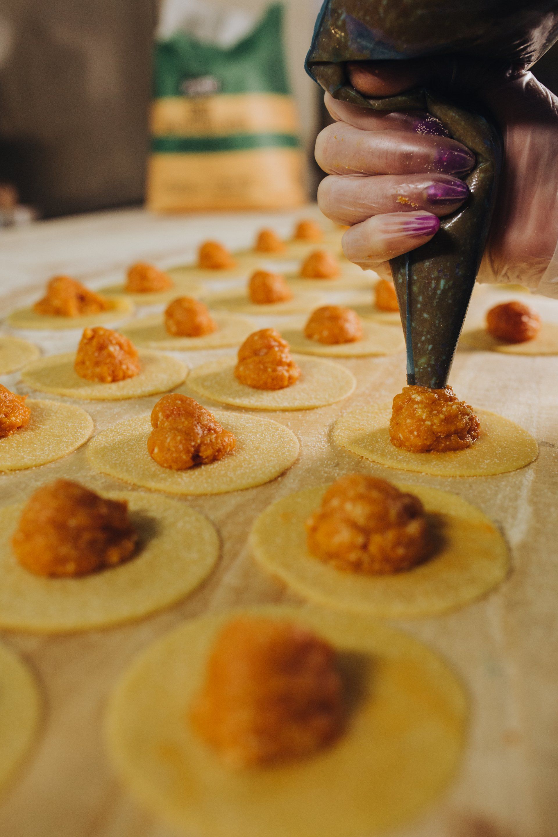 Distribuire a mano il ripieno all'arancia sulla pasta circolare e preparare i ravioli.