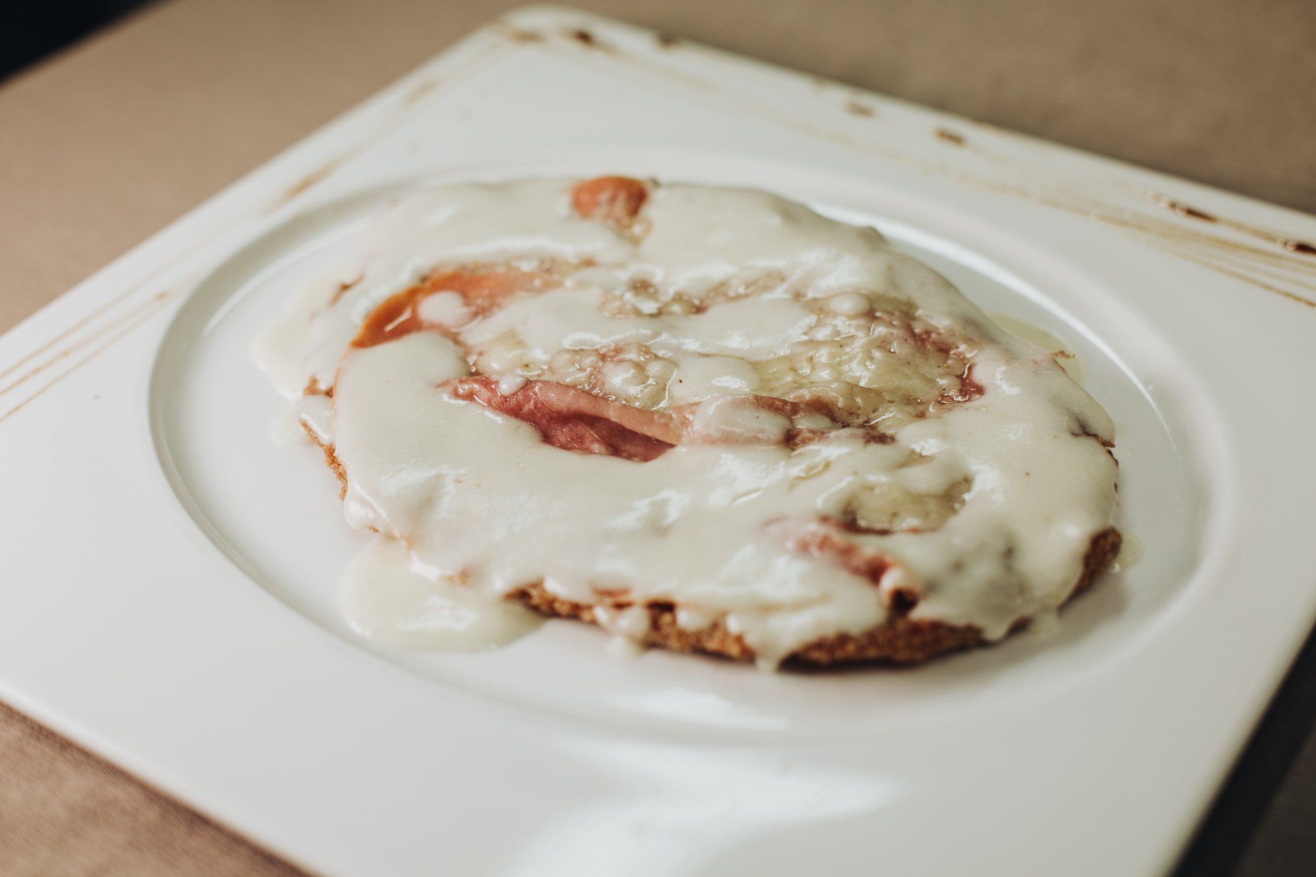 Rotolo alla cannella con ripieno rosa, glassato su un piatto bianco.