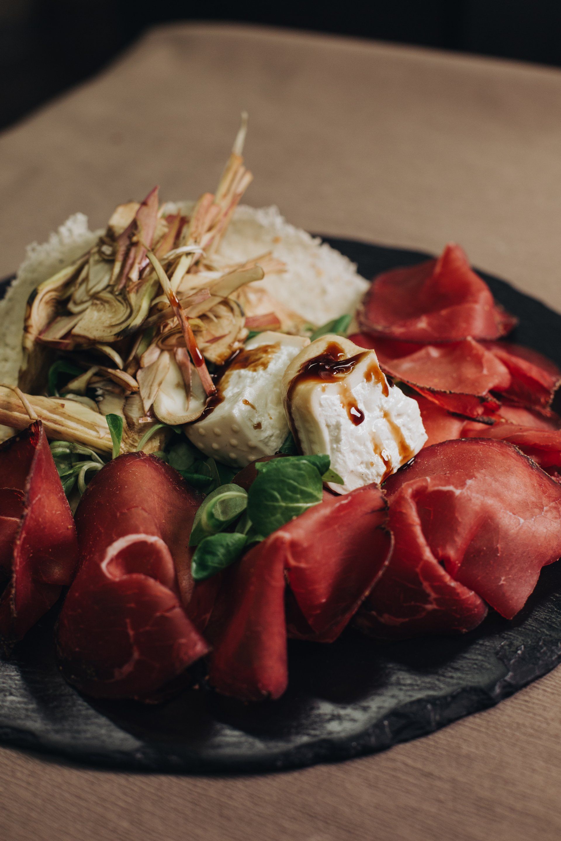 Tagliere di salumi con formaggi, carne stagionata e guarnizioni.