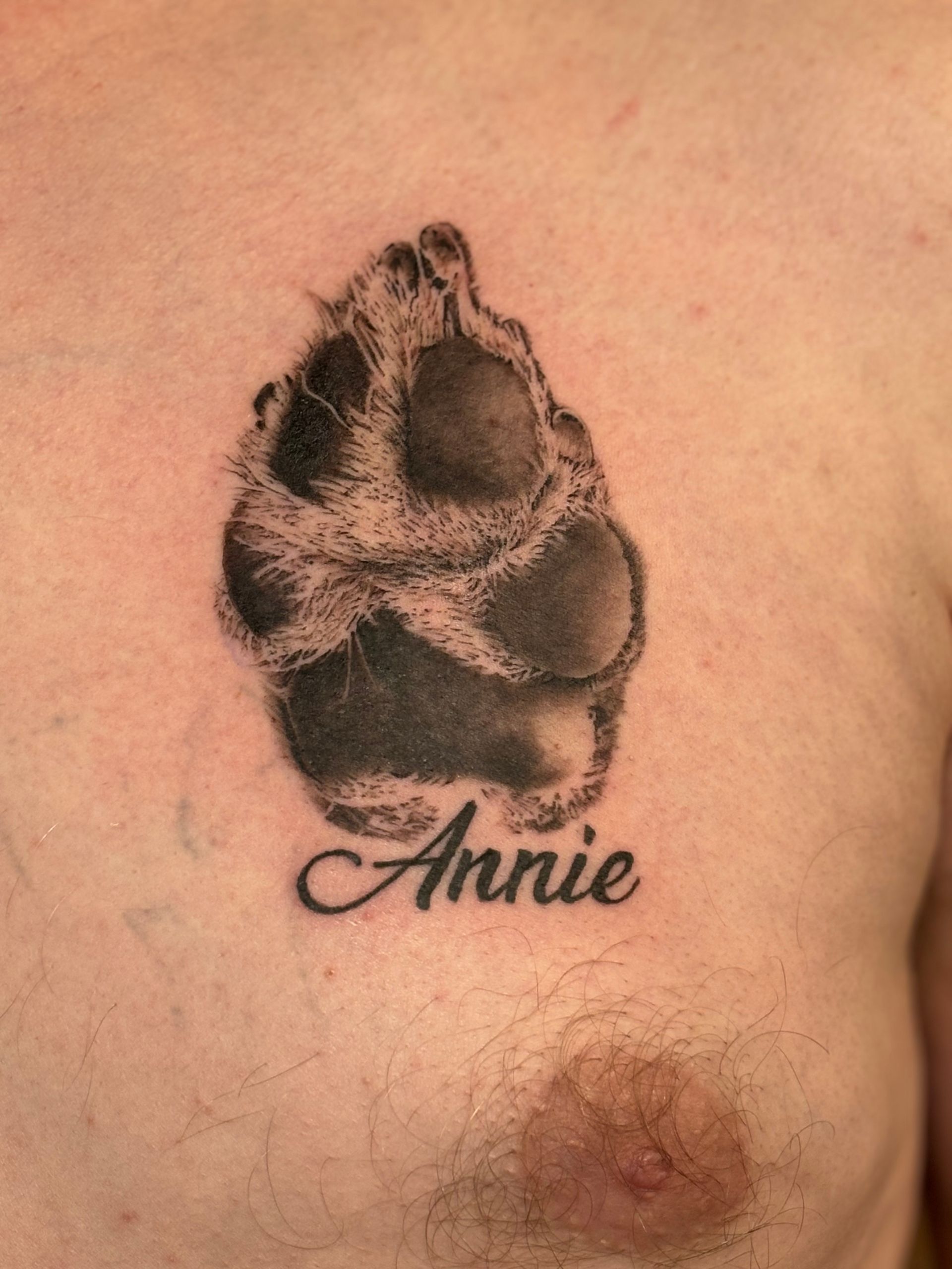 Tattoo of a dog paw print, above the word