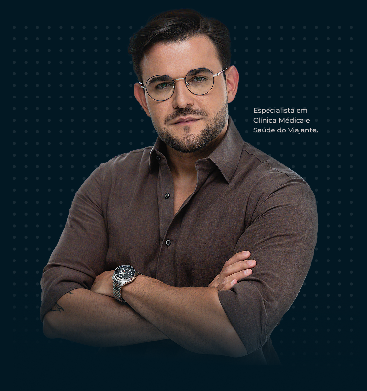 Dr. Gustavo Amarante, especialista em Clínica Médica e Saúde do Viajante, de braços cruzados, usando camisa marrom e óculos