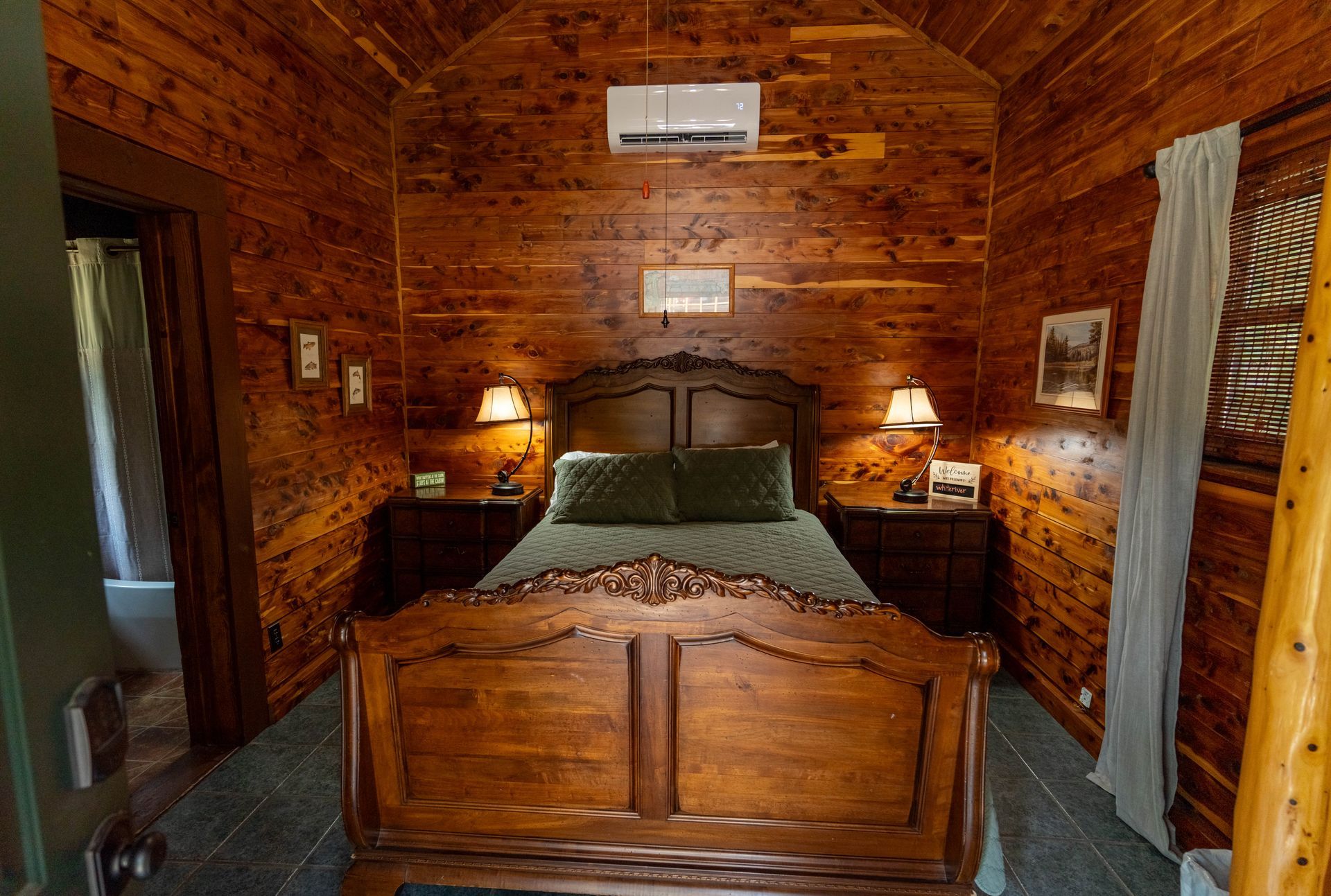Rustic wooden bedroom with carved bed, warm lamp light, and brick walls