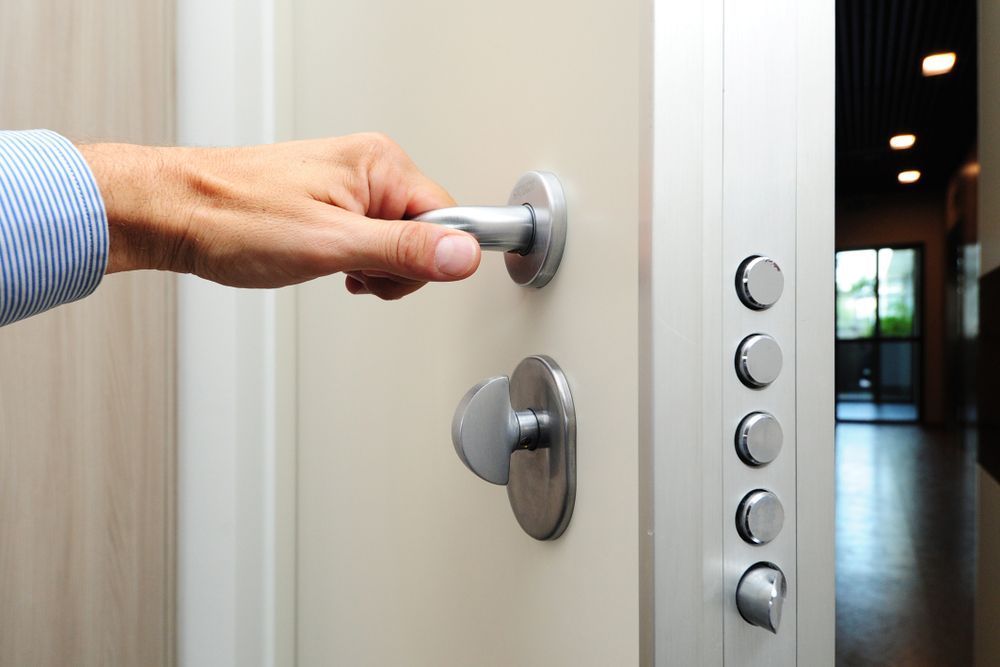 A person is opening a door with a silver handle — Locksmith in Coolangatta, QLD